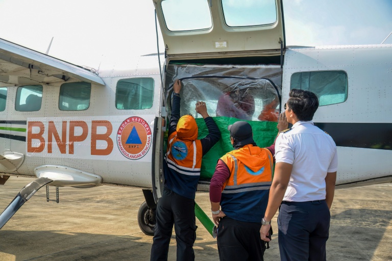 Des agents de l'Agence nationale de gestion des catastrophes chargent du chlorure de sodium dans un avion avant une opération d'ensemencement des nuages à Palangkaraya, dans le Kalimantan central, le 2 août 2026 en Indonésie