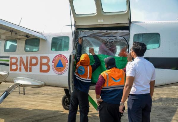 Des agents de l'Agence nationale de gestion des catastrophes chargent du chlorure de sodium dans un avion avant une opération d'ensemencement des nuages à Palangkaraya, dans le Kalimantan central, le 2 août 2026 en Indonésie
