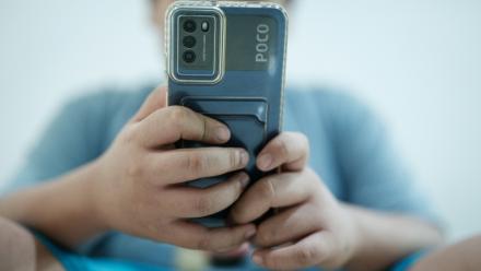 Un petit garçon regarde une vidéo sur son smartphone en attendant son père, à Jakarta, le 25 mars 2026