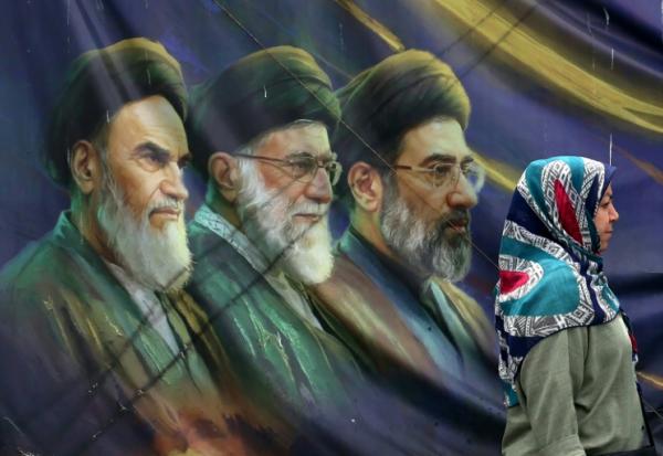Une Iranienne passe devant les portraits des trois guides suprêmes iraniens depuis l'avènement de la République islamique, le 28 mai 2026 à Téhéran