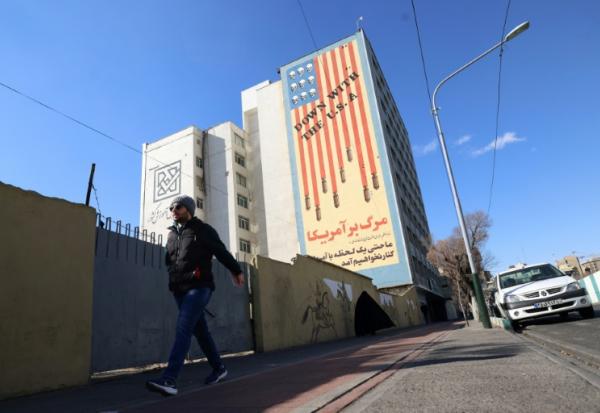 Un Iranien passe devant une immense fresque anti-américaine peinte sur un bâtiment dans la capitale iranienne, Téhéran, le 31 janvier 2026