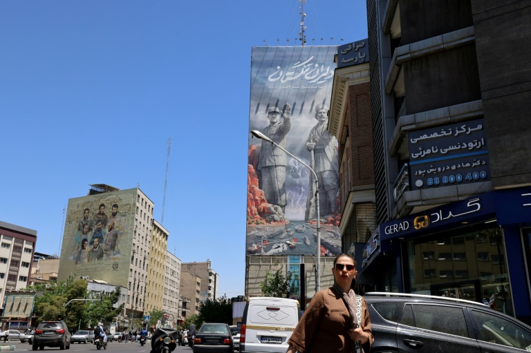 Une femme marche dans une rue près d'une immense fresque sur un immeuble faisant référence au 