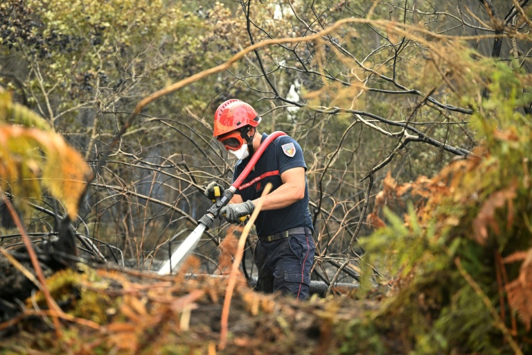Un pompier arrose le sol pour empêcher des reprises de feu, le 16 août 2026 à Luglon, dans les Landes 