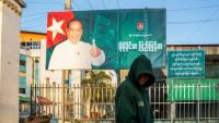Cette photo prise le 20 décembre 2025 montre un homme passer devant un panneau de campagne de Khin Yi, de l'Union pour la solidarité et le développement, dans la région de Shan en Birmanie