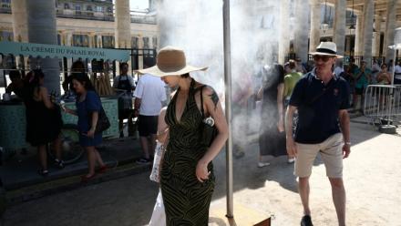 Des piétons se rafraîchissent sous un brumisateur installé par la mairie de Paris pendant une vague de chaleur à Paris, le 21 juin 2026