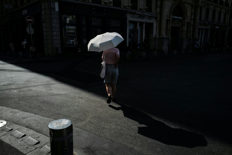 Une femme marche sous un parapluie pour se protéger du soleil lors d'une vague de chaleur à Lyon, dans le Rhône, le 24 juin 2026