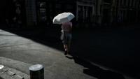 Une femme marche sous un parapluie pour se protéger du soleil lors d'une vague de chaleur à Lyon, dans le Rhône, le 24 juin 2026