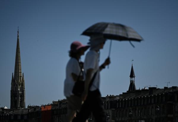 Des passants se protègent du soleil avec un parapluie à Bordeaux, le 5 juillet 2026 en Gironde, lors d'une vague de chaleur en France