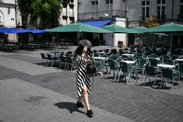 Une passante se protège du soleil avec un éventail, le 23 juin 2026 à Nantes