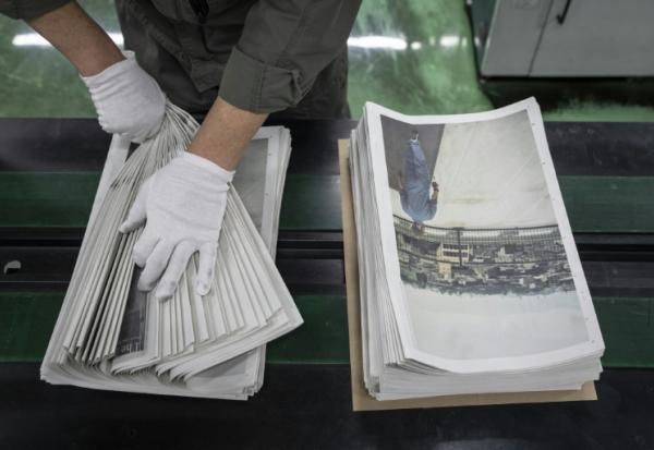 Un employé emballe l'œuvre du photographe Kazuma Obara, "The Newspaper", à Kumiyama, au Japon, le 19 mars 2026