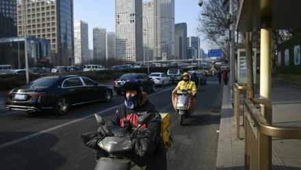 Des livreurs de repas conduisent des scooters électriques à Pékin, le 16 janvier 2024