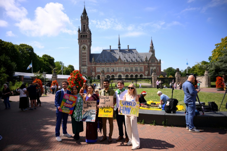 Vishal Prasad (3e à D), directeur de la campagne Pacific Island Students Fighting Climate Change, et Joie Chowdhury (2e à G), juriste de l'ONG CIEL, posent avec d'autres militants devant la Cour internationale de justice (CIJ) à La Haye, le 23 juillet 2025