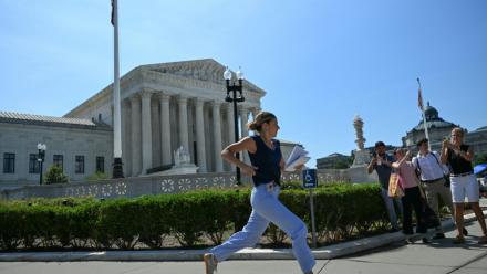 Une journaliste court devant la Cour suprême des États-Unis après qu'elle a rejeté la tentative du président Donald Trump de restreindre l'acquisition de la citoyenneté par le droit du sol, le 30 juin 2026 à Washington