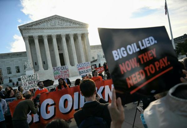 Des personnes manifestent pour dénoncer la contribution des compagnies pétrolières au changement climatique devant la Cour suprême des Etats-Unis, à Washington le 5 octobre 2026