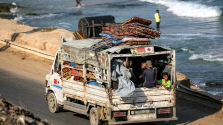 Des déplacés palestiniens fuyant le nord de la bande de Gza en direction du sud du terrtoire roulent à bord d'un camion chargé d'effets personnels sur la route côtière du camp de Nousseirat (centre), le 30 août 2025
