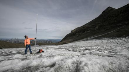 Le glaciologue Matthias Huss brandit une perche de mesure de quatre mètres de long, équivalant à la hauteur de la couche de glace ayant fondu en un an, le 24 septembre 2024 sur le glacier du Scex Rouge, en Suisse
