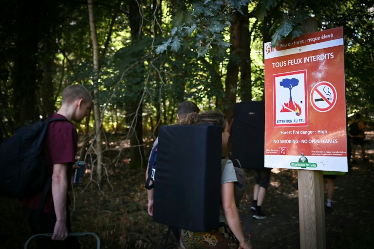 Des randonneurs passent devant devant un panneau 