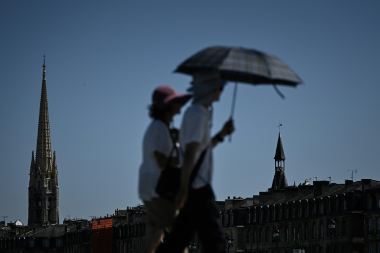 Des passants se protègent du soleil avec un parapluie à Bordeaux, le 5 juillet 2026 en Gironde, lors d'une vague de chaleur en France
