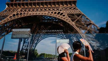 Des touristes se protègent du soleil avec des éventails en passant devant la tour Eiffel, fermée plus tôt en raison de la canicule, le 11 juillet 2026 à Paris