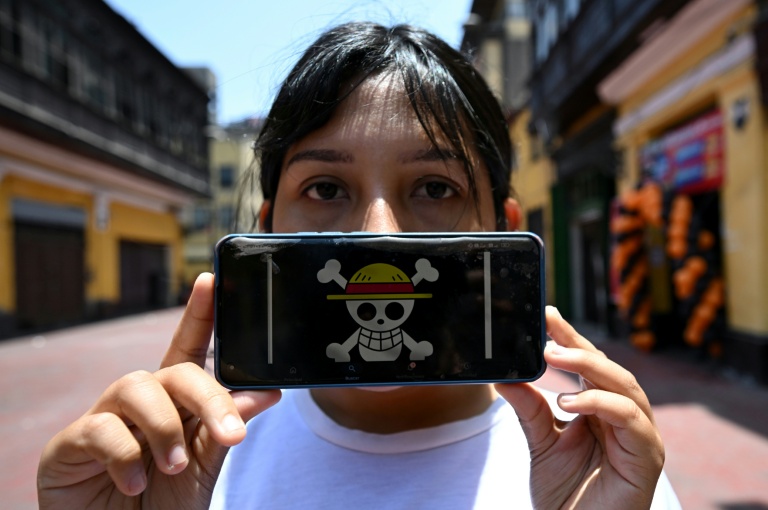 Rosalinda, diplômée en droit et membre du mouvement Gen Z, montre le drapeau du manga One Piece sur son téléphone portable lors d'une interview avec l'AFP à Lima, le 19 octobre 2025 au Pérou