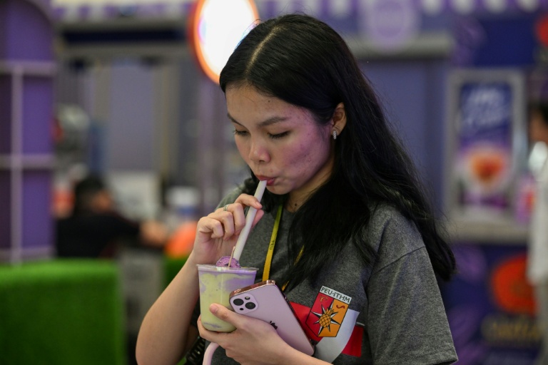 Une cliente boit une boisson à l'ube et au matcha dans un centre commercial de Quezon City, dans la métropole de Manille, le 23 septembre 2026 aux Philippines