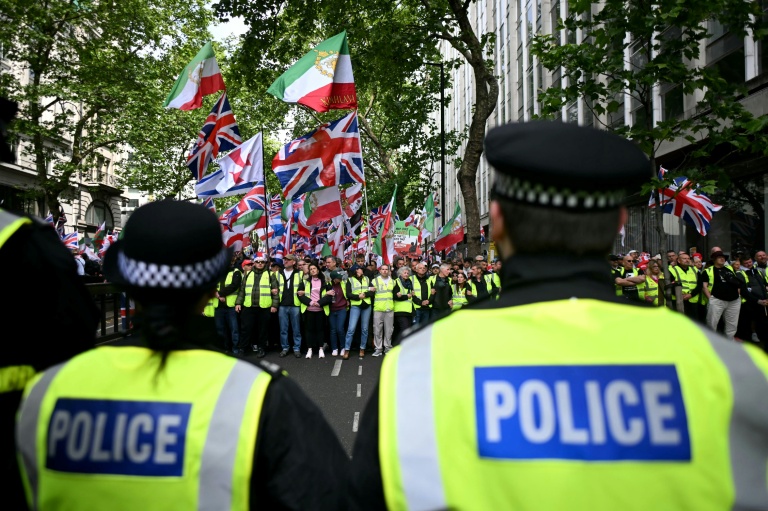 Des policiers face à des partisans de Tommy Robinson, militant d'extrême droite britannique, rassemblés pour une marche organisée par Unite The Kingdom, le 16 mai 2026 à Londres