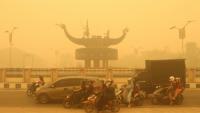 Des motocyclistes portant un masque de protection circulent dans une épaisse brume causée par des feux de forêt et de terres dans la région de Palangkaraya, dans le Kalimantan central, le 24 octobre 2026 en Indonésie