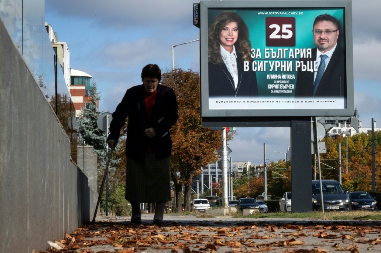 Une personne marche devant une affiche électorale de la présidente sortante de Bulgarie, Iliana Iotova, et de son vice-président candidat Kiril Valchev, à Sofia, le 23 octobre 2026