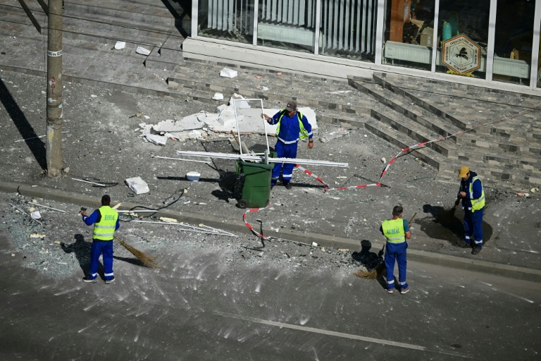 Des employés municipaux dégagent les débris de la rue après qu'un drone russe a percuté un immeuble d'habitation à Galati, le 29 mai 2026 dans l'est de la Roumanie