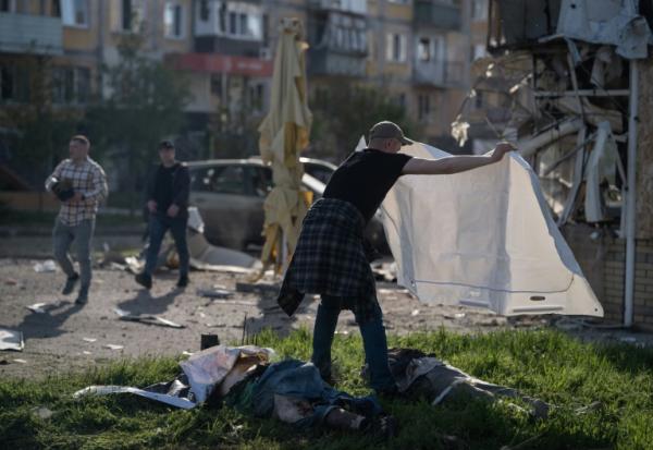 Un homme couvre d'un drap les corps de victimes de frappes russes à Kramatorsk, dans l'Est de l'Ukraine, le 5 mai 2026