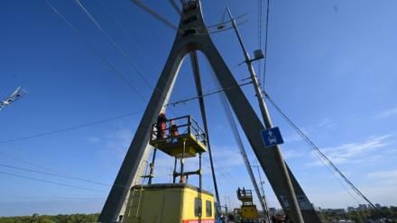Des techniciens réparent une ligne électrique de trolleybus à proximité des dégâts constatés sur un pilier du pont, à la suite d’une attaque de drone contre le pont du Nord à Kiev, le 3 octobre 2026