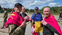 Photo diffusée par le Quartier général de coordination pour le traitement des prisonniers de guerre, le 19 août 2026, montrant d'anciens prisonniers de guerre ukrainiens, enveloppés dans des drapeaux nationaux, près d'un bus après un échange effectué dans un lieu tenu secret