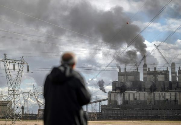 Un homme observe la fumée noire s'échappant de la centrale électrique au charbon d'Afsin-Elbistan, dans la province d'Elbistan, le 11 février 2026 en Turquie