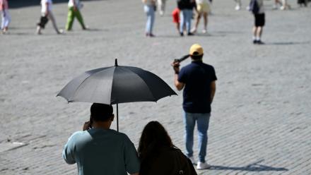 Des touristes visient Bruxelles à l'abri sous un parapluie pour se protéger du soleil lors d'une vague de chaleur le 27 mai 2026, en Belgique