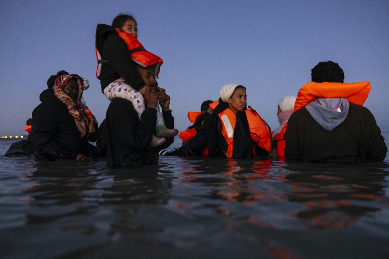 Des migrants avancent dans l'eau pour essayer de monter à bord d'un 