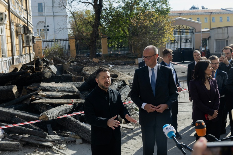 Le président ukrainien Volodymyr Zelensky (G) et le chancelier allemand Friedrich Merz (D) lors d'une visite du bâtiment endommagé de l'Académie des sciences de Kiev, le 4 octobre 2026 
