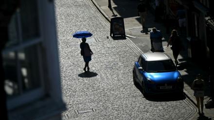 Une personne se protège du soleil sous une ombrelle, le 25 juin 2026 à Guildford, au Royaume-Uni, lors d'un épisode de canicule en Europe
