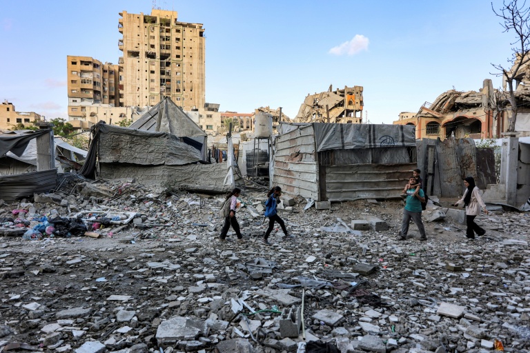 Des habitants passent devant un immeuble résidentiel touché la veille par une frappe israélienne dans le quartier d'Al-Ramal à Gaza, le 16 mai 2026