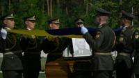 Des militaires de la garde d’honneur ukrainienne tiennent des drapeaux nationaux au-dessus des cercueils contenant les dépouilles d’Andriy Melnyk, mort en 1964 et chef d’une branche de l’Organisation des nationalistes ukrainiens (OUN) lors de leur cérémonie de réinhumation au cimetière militaire national près de Kiev, le 25 mai 2026