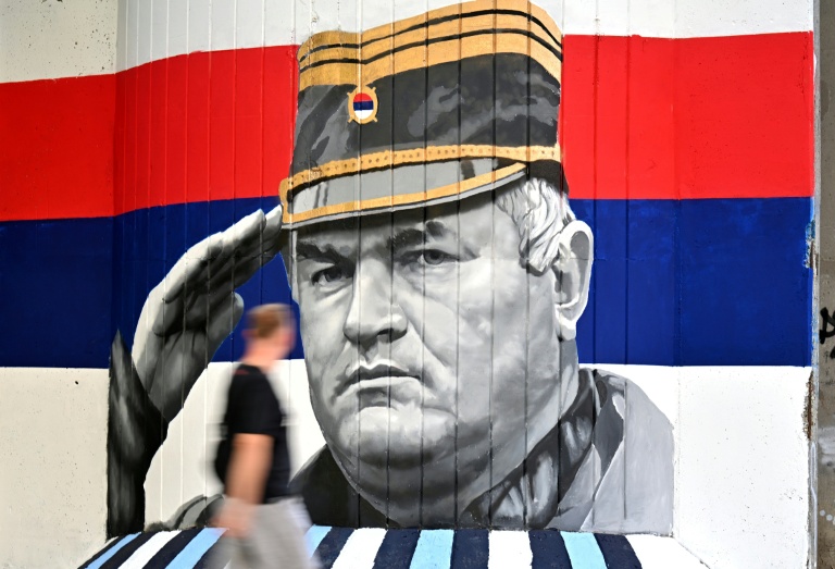 Un homme passe devant une fresque murale représentant l'ancien chef militaire des Serbes de Bosnie, Ratko Mladić, le 6 septembre 2026 à Belgrade, en Serbie, dont l'inhumation est prévue le 7 septembre 2026 au cimetière de Topčider à Belgrade, sur fond de critiques de l'UE concernant la 