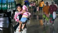 Une femme, un enfant dans les bras, se dirige vers un abri à l'approche du cyclone Arnab, le 27 octobre 2026 à Kakinada, dans l'Etat de l'Andhra Pradesh, en Inde