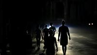Des habitants marchent dans une rue de La Havane pendant une panne d'électricité, le 13 mai 2026 à Cuba