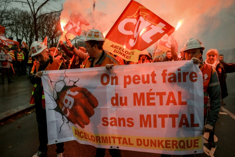 Des employés d'ArcelorMittal défilent derrière une banderole lors d'une action organisée par la CGT sur l'Esplanade des Invalides, à Paris, le 27 novembre 2025