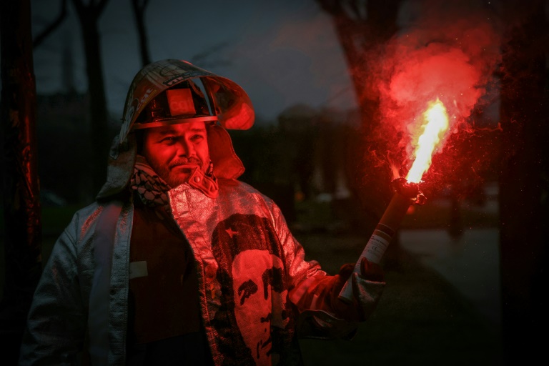 Un employé d'ArcelorMittal, portant son équipement de protection orné d'autocollants de la CGT et d'un portrait du révolutionnaire argentin Ernesto Che Guevara, participe à une action organisée par la CGT sur l'Esplanade des Invalides, à Paris, le 27 novembre 2025, afin de soutenir le projet de loi LFI de nationalisation d'ArcelorMittal France