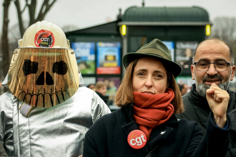 Sophie Binet, secrétaire générale de la CGT, lève le poing à côté d'un employé d'ArcelorMittal portant un masque de soudeur lors d'une action rassemblant des employés d'ArcelorMittal sur l'Esplanade des Invalides à Paris le 27 novembre 2025.