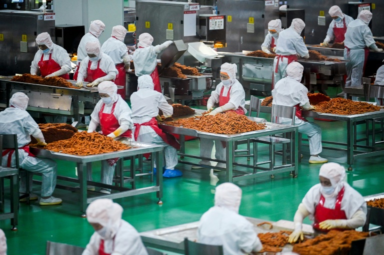 Des ouvriers préparent des lamelles de farine pour les aromatiser avant leur conditionnement à l'usine Mala Wangzi, du comté de Pingjiang, dans la province du Hunan, le 17 juin 2026 dans le centre de la Chine