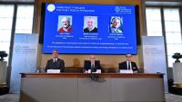 Un écran affiche les portraits des lauréats du prix Nobel de Physique 2025 (g-d) Le Britannique John Clarke, le Français Michel H Devoret et l'Américain John M Martinis lors d'une conférence de presse à l'Académie royale des sciences de Suède, le 7 octobre 2025 à Stockholm
