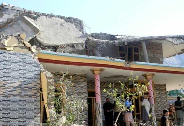 Des Afghans se rassemblent devant une maison endommagée par une frappe pakistanaise à Asadabad dans l'est de l'Afghanistan le 25 novembre 2025
