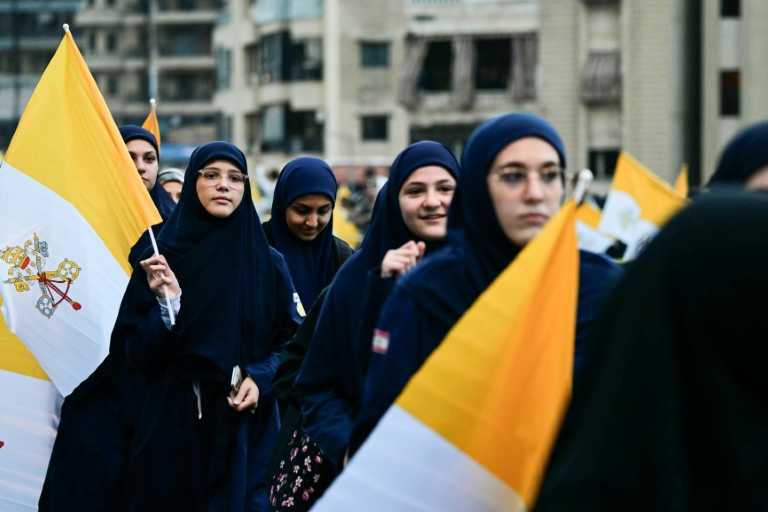 Des femmes musulmanes libanaises tiennent des drapeaux du Vatican en attendant l'arrivée du pape Léon XIV dans la banlieue sud de Beyrouth, un quartier résidentiel connu sous le nom de Dahiyeh, bastion du Hezbollah, le 30 novembre 2025 au Liban