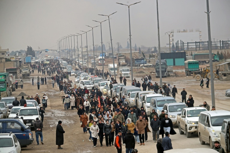 Des habitants accueillent un convoi ramenant des combattants kurdes d'Alep après des jours de combat avec les forces gouvernementales dans la ville syrienne sous contrôle kurde de Qamishli, le 11 janvier 2026